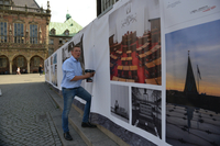 Bürgerschaftspräsident Frank Imhoff schraubt die Banner am Bauzaun fest.