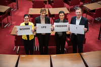 Parisa Fathi, Padideh Forouhid, Shirin Dezfouli und Frank Imhoff stehen nebeneinander im Plenarsaal. Sie halten Schilder mit den Aufdrucken "Woman", Lif" und "Freedom" in die Kamera.