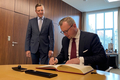 Der polnische Generalkonsul sitzt an einem Tisch und trägt sich in ein Gästebuch ein. Neben ihm steht Frank Imhoff und schaut zu.