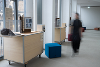 Eine Person mit verschwommener Silhouette läuft durch einen hellen Ausstellungsraum.