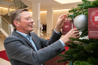 Frank Imhoff hängt Wunschzettel an einen geschmückten Tannenbaum im Foyer der Bürgerschaft.