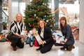 Susanne Eilers, Antje Grotheer und Sylvia Schikker knieben nebeneinander vor derm  Wunschbaum. Alle halten ein verpacktes Geschenk in ihren Händen.