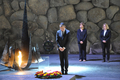 Im steht mit gesenktem Kopf vor einem niedergelegten Kranz neben der ewigen Flamme in der Halle der Erinnerung in Yad Vashem. Im Hintergrund stehen Sülmez Dogan und Antje Grotheer. Alle tragen dunkle Kleidung.