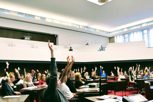 Jugendliche sitzen im Plenarsaal und stimmen über etwas ab