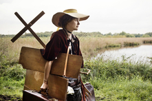 Filmszene: Carla Juri als Paula Modersohn-Becker läuft mit Taschen und Malutensilien bepackt durch die Worpsweder Landschaft.