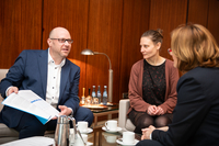 Steffen Bothe und Esther Binner sitzen gemeinsam mit der Präsidentin in der Sitzgruppe im Präsidentinnenzimmer. Steffen Bothe präsentiert den Jahresbericht. Auf dem Tisch stehen Kaffeetassen.