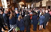 Viele Abgeordnete und Politiker/-innen sowie Fernsehkameras umringen den neu gewählten Bürgermeister in der historischen Rathaushalle.