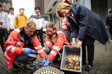 Mitarbeiter:innen vom Roten Kreuz leeren das Bremer Loch. Antje Grotheer steht daneben und hält eine Kiste voller Münzen in den Händen.